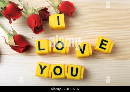 Belle rose con frase 'i Love You' su sfondo tavolo di legno Foto Stock