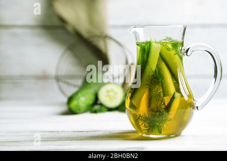 Cuocitore di vetro con acqua fresca di cetriolo biologico su tavolo di legno Foto Stock