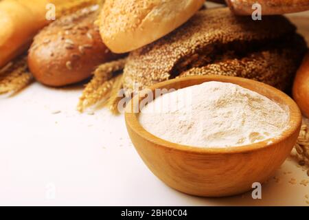 Pane fresco con frumento, sesamo, semi di girasole e ciotola di farina in legno, primo piano Foto Stock