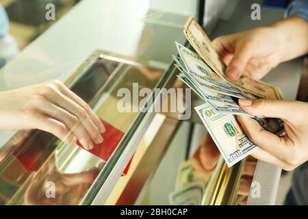 Mano femminile con denaro in sportello cassa. Concetto di cambio valuta Foto Stock