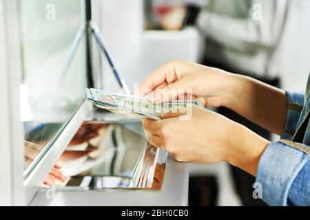 Mano femminile con denaro in sportello cassa. Concetto di cambio valuta Foto Stock