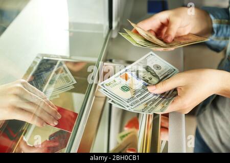 Mano femminile con denaro in sportello cassa. Concetto di cambio valuta Foto Stock