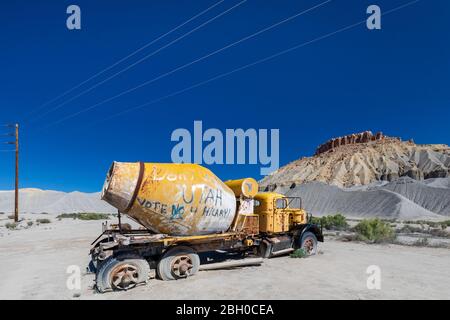 Un vecchio e arrugginito camion betoniera si trova abbandonato in una cava di ghiaia in Utah, sotto un cielo estivo blu Foto Stock