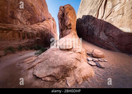 Un'ampia inquadratura angolare di una grande formazione di arenaria rossa Nel mezzo di un canyon nel sentiero del Giardino del Diavolo Al Parco Nazionale di Arches Foto Stock