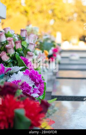 Bouqets di fiori che posano su lapidi come decorazione. Posto nella memoria dei cari perduti Foto Stock