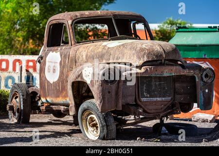 Primo piano di un vecchio camion del raccoglitore arrugginito e rovinato con una ruota mancante e un badge della Route 66 dipinto sulla porta del passeggero Foto Stock