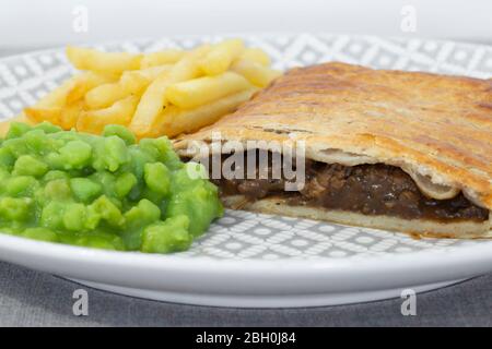 Torta di bistecca e cipolla con patatine fritte e piselli funghi. Su tovaglia di color grigio marl Foto Stock