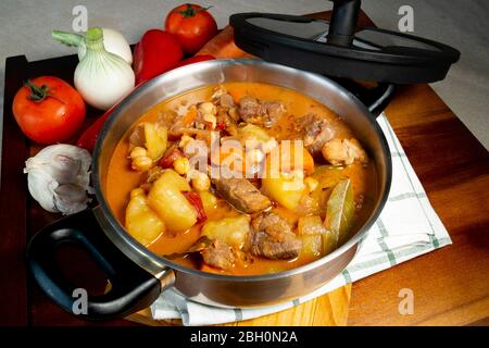 Stufato di manzo in un grande vaso con verdure e un tavolo di legno, visto direttamente dall'alto, parte di una serie Foto Stock