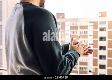 uomo irriconoscibile che si aggrappava gli operatori sanitari dal suo balcone per il loro lavoro durante la pandemia di coronavirus, concetto di quarantena e confinamento Foto Stock