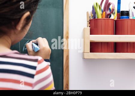 disegno bambino irriconoscibile su una lavagna, disegno e concetto artigianale a casa Foto Stock