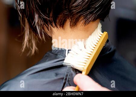 Hand os parrucchiere sta pulendo il collo con spazzola dai capelli tagliati dopo il taglio. Foto Stock