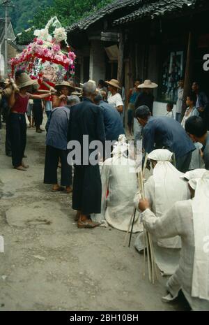 Cina, provincia di Guangxi, Fuli, lutto della processione funebre inginocchiati davanti al bara coperto di fiori portato dietro. . Foto Stock