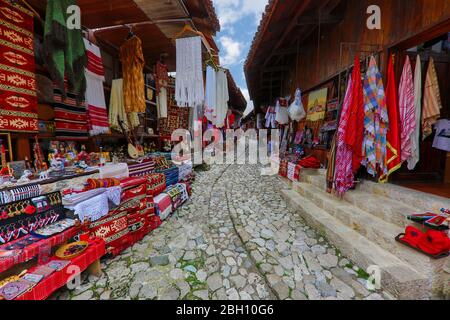 Negozi di tessili in strada acciottolata nella città vecchia di Kruje, Albania Foto Stock