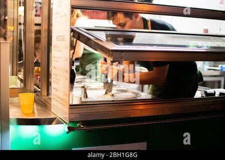 Uomo che prepara il gelato durante il festival fast food Foto Stock