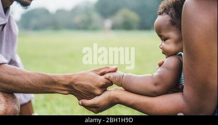 Happy african famiglia aziende mani insieme all'aperto durante la giornata della madre - mamma, padre e figlia che hanno momenti teneri nel parco verde della natura - Amore An Foto Stock