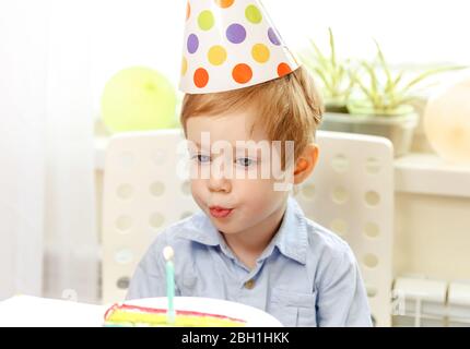 Il ragazzo fa un desiderio e soffia la candela alla torta di compleanno. Festa Foto Stock