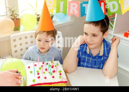 Due ragazzi belli sorridenti alla festa di compleanno. Torta di compleanno Foto Stock