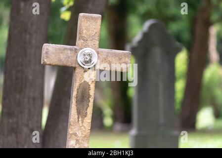 Vecchio cimitero nel centro di Bratislava. Il monumento è coperto di muschio. Croce con un piccolo bassorilievo. Foto Stock