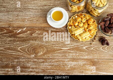 immagine di uno spuntino per rompere il veloce. tradizionale spuntino islamico nastar asiatico servito con tè su sfondo di legno Foto Stock