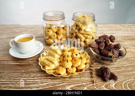 immagine di uno spuntino per rompere il veloce. tradizionale spuntino islamico nastar asiatico servito con tè su sfondo di legno Foto Stock