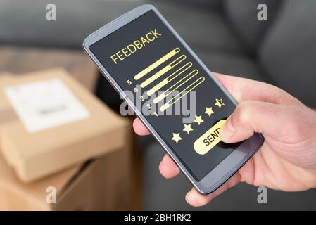 primo piano della persona che fornisce feedback positivi sullo smartphone dopo la consegna degli articoli ordinati, la revisione del cliente e il concetto di feedback Foto Stock