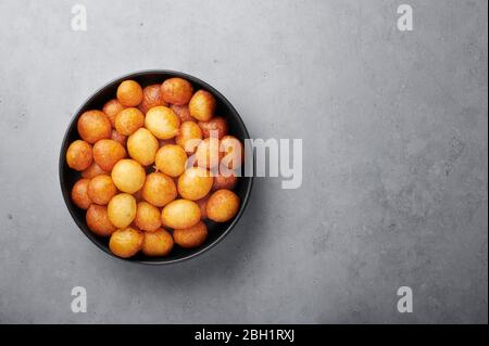 Loukoumades o luqaimat o lokma in ciotola nera su fondo grigio cemento. Loukoumades è donunts cucina orientale popolare durante Ramazan. RAM popolare Foto Stock