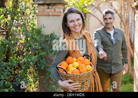 Coppia felice che tiene un cestino con limoni e arance Foto Stock