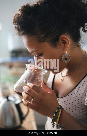 Donna che lavora in una maestria del caffè che odora il caffè Foto Stock