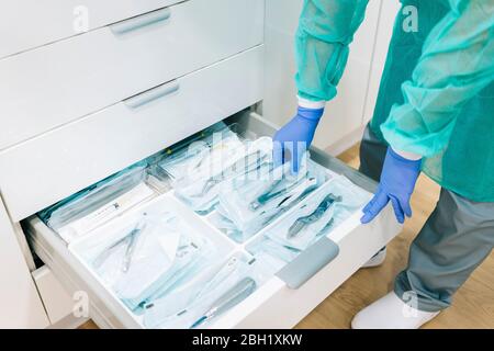 Medico che prende gli strumenti sterili dalla cabina Foto Stock