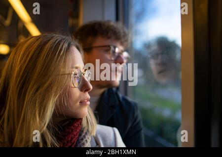 Giovane donna pusiva seduta in tram con il suo ragazzo che guarda fuori dalla finestra Foto Stock