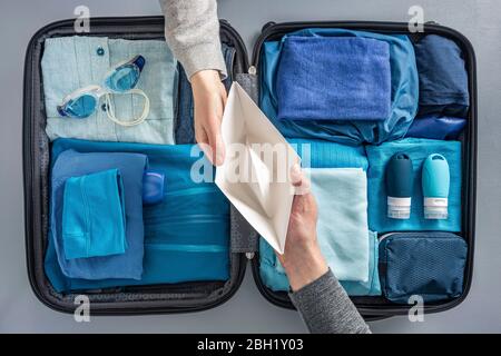 Vista dall'alto della donna che consegna l'imbarcazione di carta all'uomo sopra la valigia imballata Foto Stock