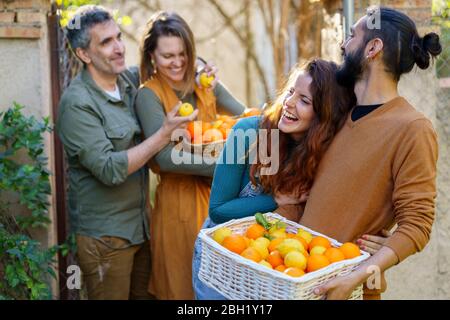 Amici felici che tengono un cestino con limoni e arance Foto Stock