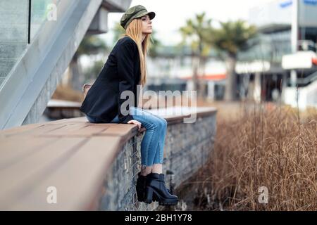 Giovane bionda che si rilassa su una panchina Foto Stock