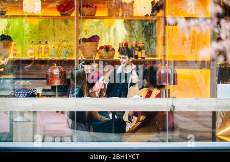 Amici che si incontrano in un bar alla moda, ridendo e parlando Foto Stock