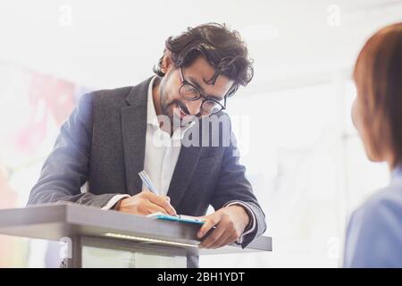 Paziente che compila il modulo presso la reception di una pratica dentale Foto Stock
