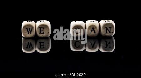 blocchi di legno con il testo che possiamo su uno sfondo nero Foto Stock