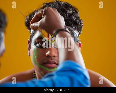 Primo piano di un ballerino Kathakali ottenere il suo trucco fatto. Foto Stock