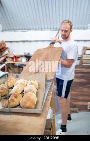 Panettiere che cuoce piccole focacce di pane in panetteria Foto Stock