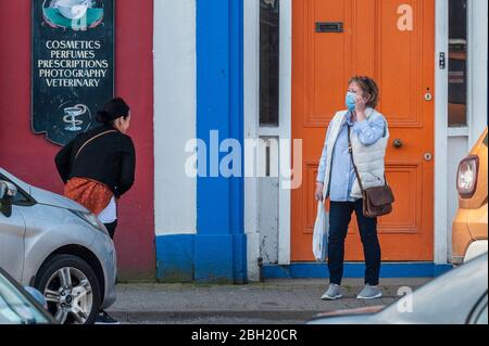 Bantry, West Cork, Irlanda. 23 aprile 2020. Una donna parla con il suo amico in una piazza di Bantry quasi deserta che indossa una maschera facciale e guanti usa e getta per proteggersi da Covid-19. Credit: AG News/Alamy Live News Foto Stock