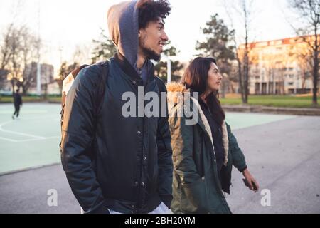 Giovane coppia che cammina al campo di pallacanestro Foto Stock
