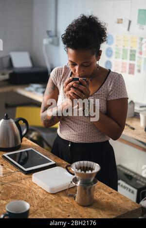 Donna che lavora in una maestria del caffè che odora il caffè Foto Stock