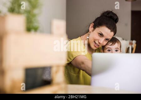 Madre e bambino durante una videochiamata sul computer portatile a casa Foto Stock