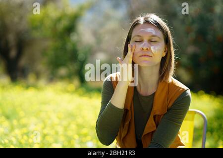 Giovane donna che applica la protezione solare in campagna Foto Stock