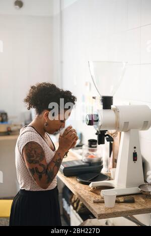 Donna che lavora in una maestria del caffè che odora il prodotto Foto Stock
