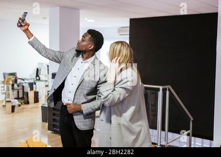 Giovane uomo d'affari e donna d'affari che prende un selfie in ufficio Foto Stock