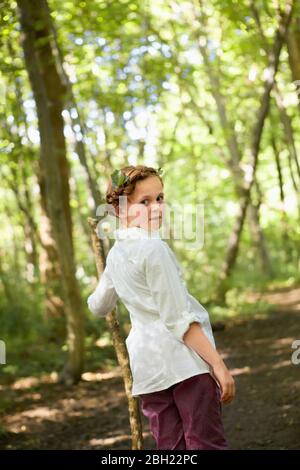 Ritratto di ragazza con bastone di legno che cammina nella foresta Foto Stock