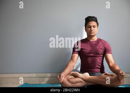 Uomo seduto in sukhasana durante la meditazione. Foto Stock