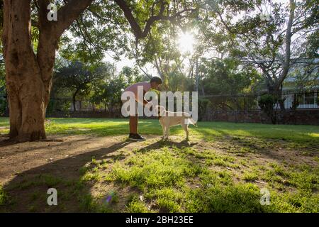 Uomo che gioca con il suo cane in giardino. Foto Stock