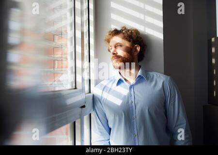 Ritratto di imprenditore guardando fuori della finestra Foto Stock