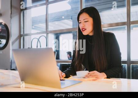 Imprenditrice utilizzando laptop in un cafe Foto Stock